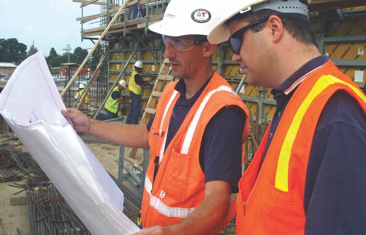 two engineers looking at blueprints at a construction site